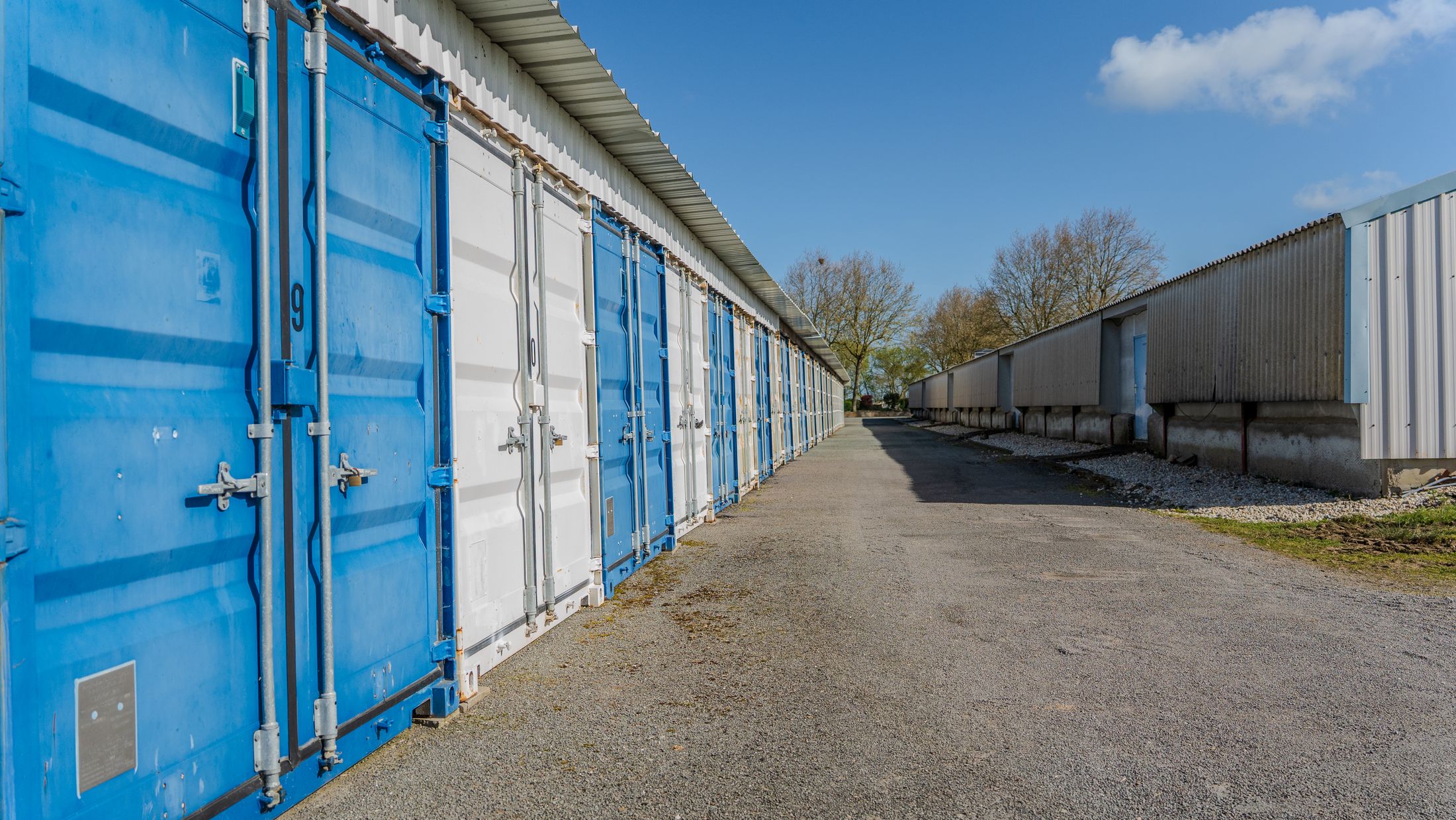 Rangée de conteneurs bleus et blancs le long d’une allée